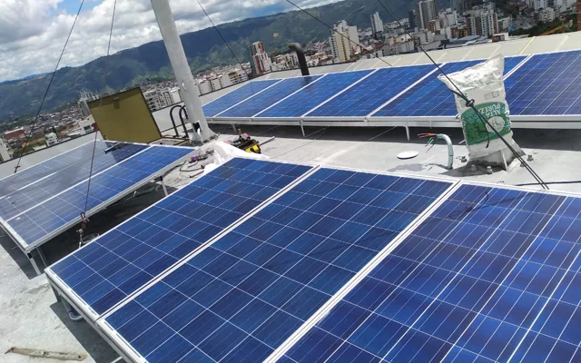 Paneles solares instalados en una azotea con la ciudad al fondo